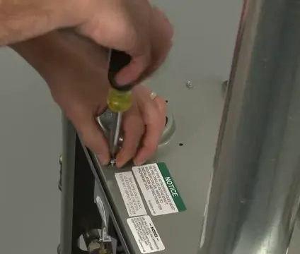 Unthreading the screws using a flat head screwdriver